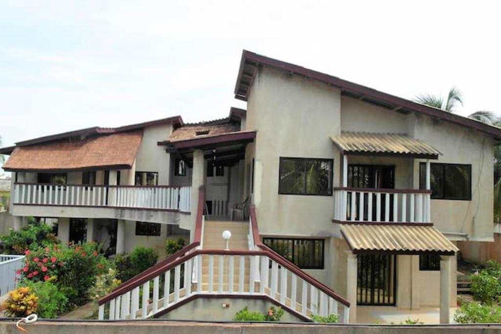 a large house with a staircase in front of it at Appartement confortable à Grand Popo, 50 m², piscine partagée in Grand-Popo