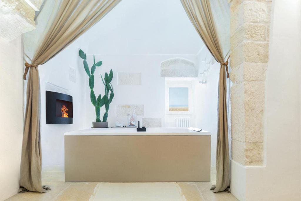 a white room with a table with a plant on it at BELLE HOME OSTUNI vasca vista mare in Ostuni