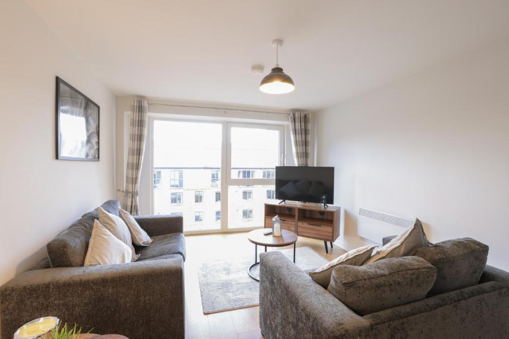 a living room with two couches and a television at Southbank Leeds Apartment. New! With Free Parking in Leeds