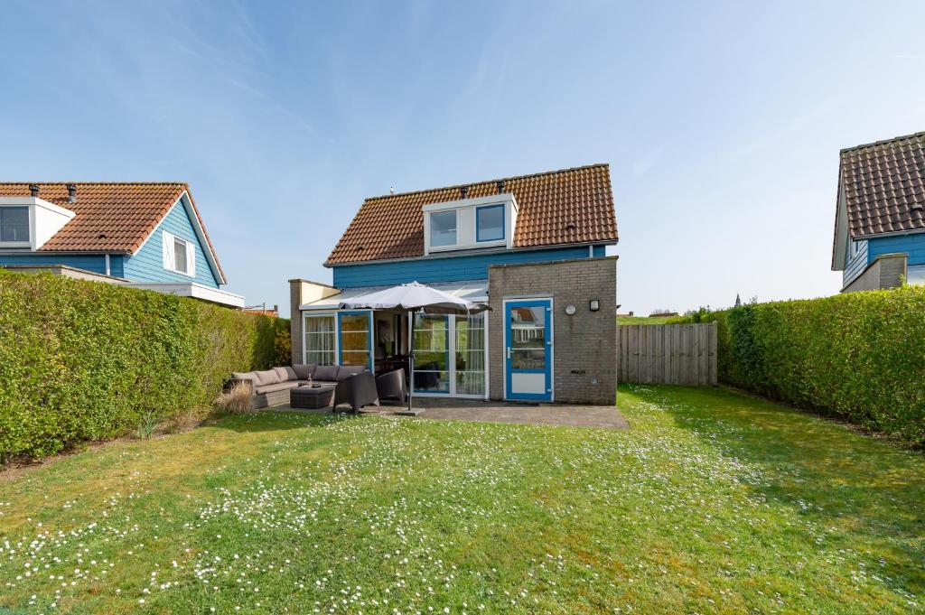 a house with a blue door and a yard at Antibes 240 - Kustpark Village Scaldia in Hoofdplaat