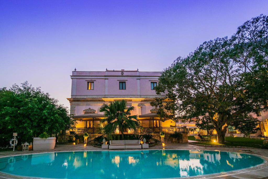 a building with a swimming pool in front of a building at Hotel Parco delle Fontane in Syracuse