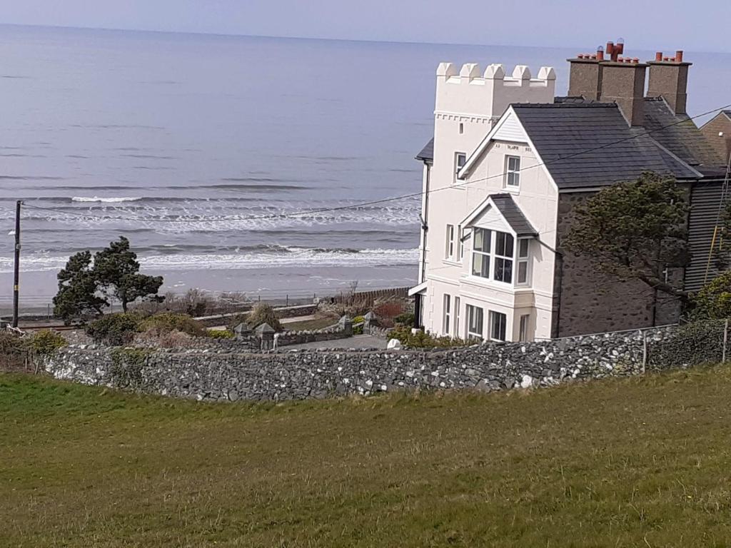 a white house on a hill next to the ocean at Talarfor Barmouth in Barmouth