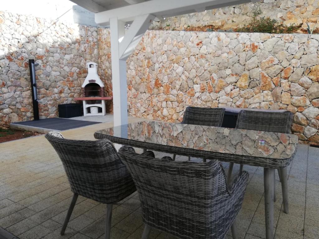 a table and chairs in front of a stone wall at FRANTA in Cres