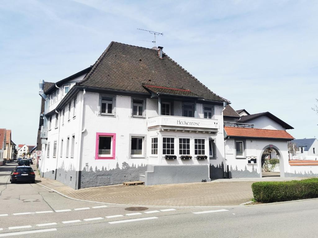 a white building with a black roof on a street at Self CheckIn Hotel Heckenrose Lorin in Ringsheim