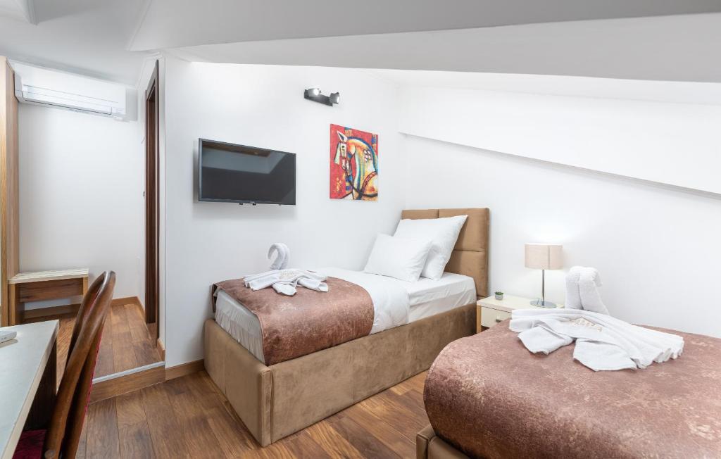a hotel room with two beds and a flat screen tv at Hotel Dua Residence in Poreč