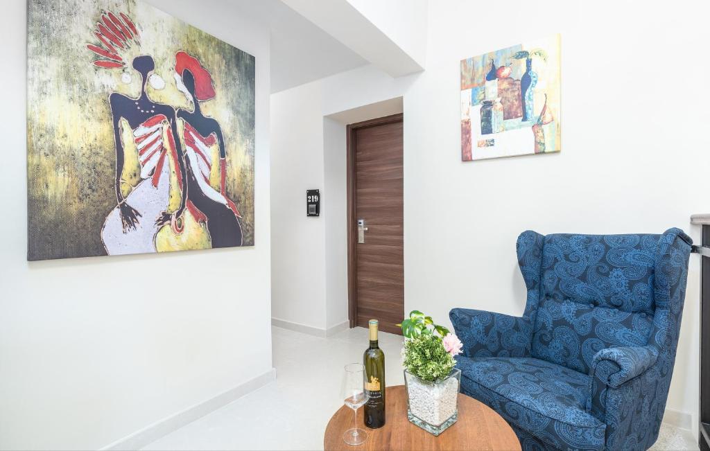 a living room with a blue chair and a painting at Hotel Dua Residence in Poreč