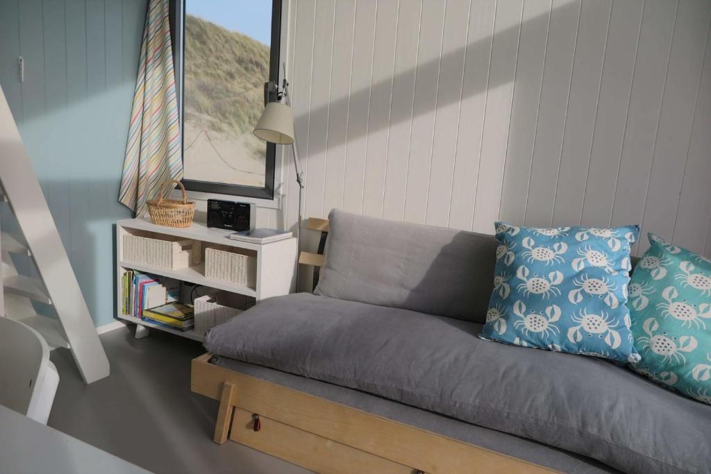 ein Wohnzimmer mit einem Sofa und einem Fenster in der Unterkunft Slaapstrandhuisje - Strand dishoek 60 Dishoek in Vlissingen