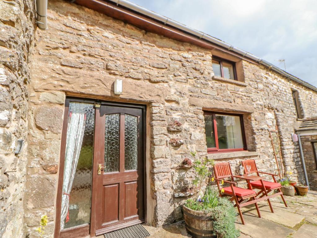 a stone house with a wooden door and chairs at Old Cottage in Nateby