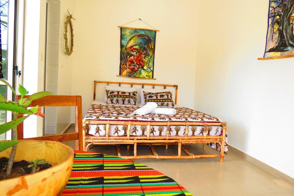 a bedroom with a bed with a painting on the wall at KASA BOUBAK in Kafountine