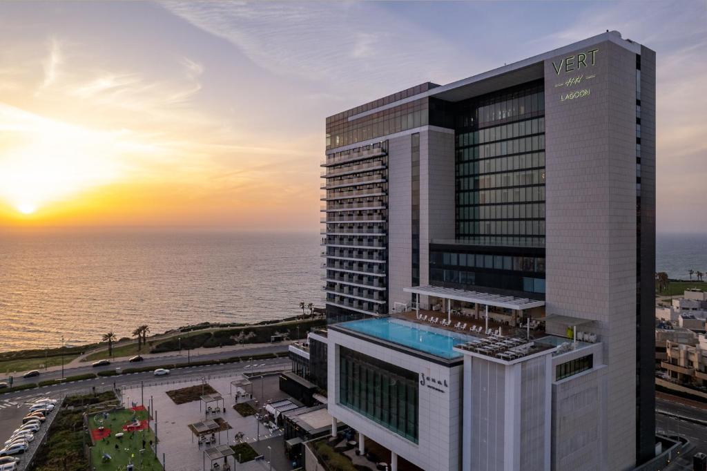 a view of a building with the ocean in the background at Vert Lagoon Netanya By AFI Hotels in Netanya