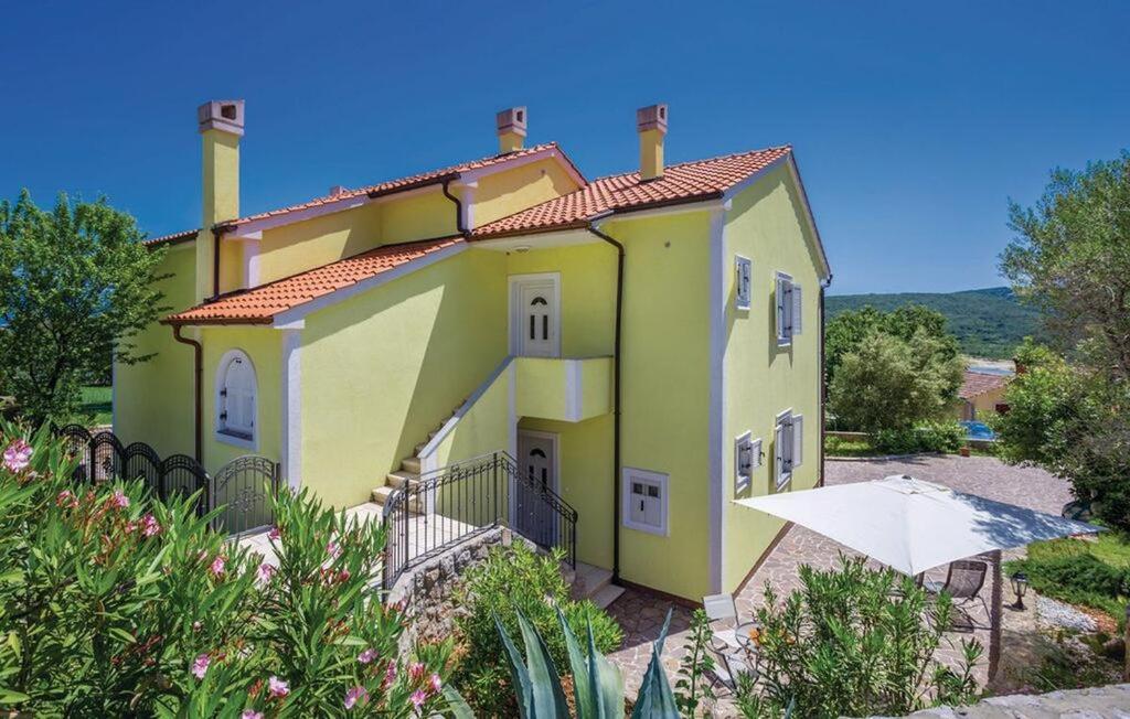 ein großes gelbes Haus mit einem Tisch davor in der Unterkunft Apartmani Agava in Čižići