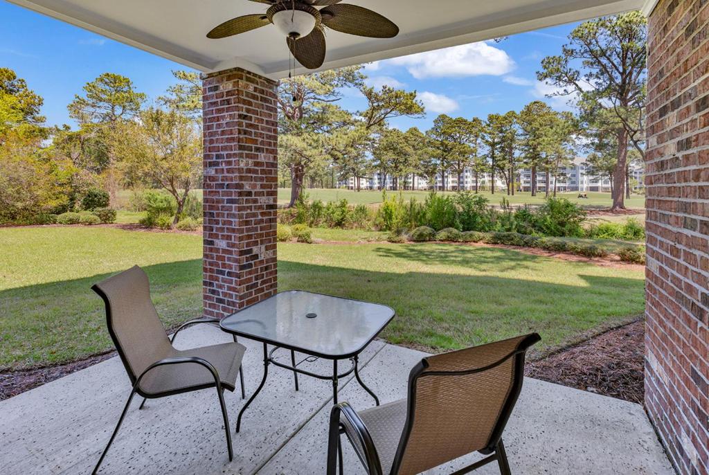 a patio with chairs and a table and a ceiling fan at Tranquil 3BR Condo in Magnolia Pointe near Myrtlewood Golf Resort in Myrtle Beach