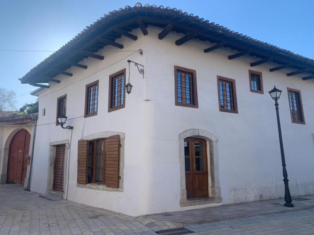 a white building with wooden windows and a street light at Rooms for Rent in Shkodër