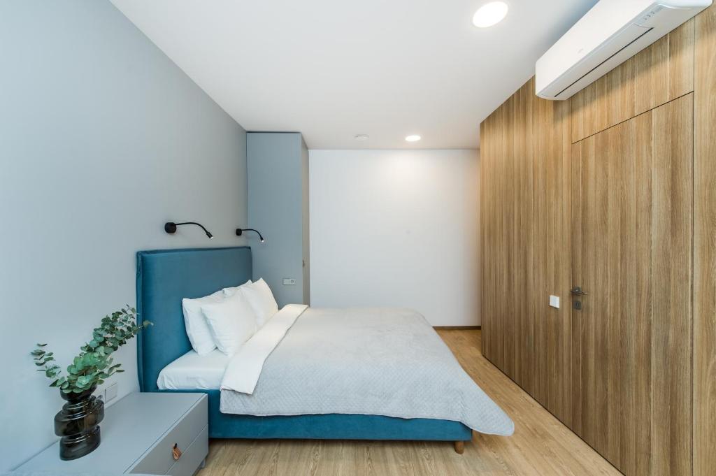 a bedroom with a blue bed and a wooden door at River city apartments No 3 by URBAN RENT in Kaunas