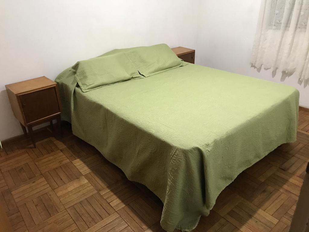 uma cama com uma colcha verde e duas mesas de cabeceira em Biloba em Colônia do Sacramento