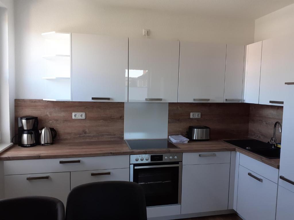 a kitchen with white cabinets and a wooden counter top at Ferienwohnung Krabbe in Wilhelmshaven