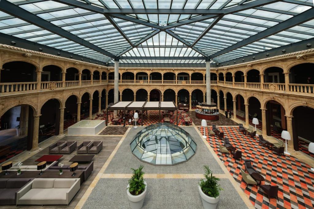 un grand bâtiment avec un plafond en verre, des tables et des chaises dans l'établissement Castilla Termal Burgo de Osma, à El Burgo de Osma