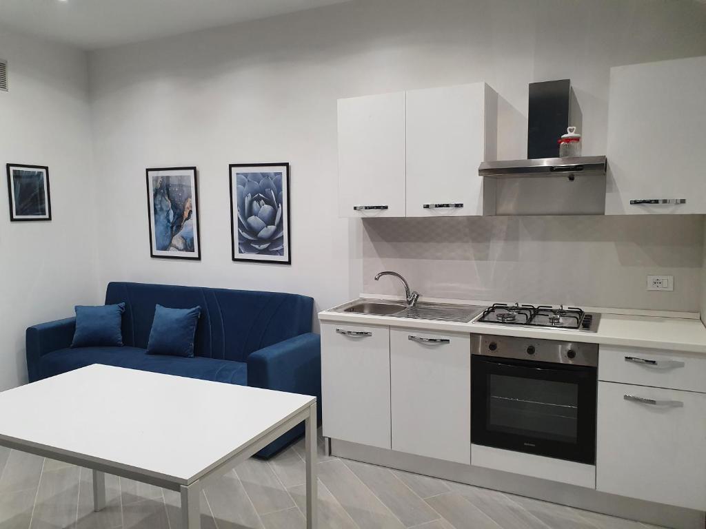 a kitchen with a stove and a blue couch at Airport Home TUREI & BRINGO Car Rental in Cinisi