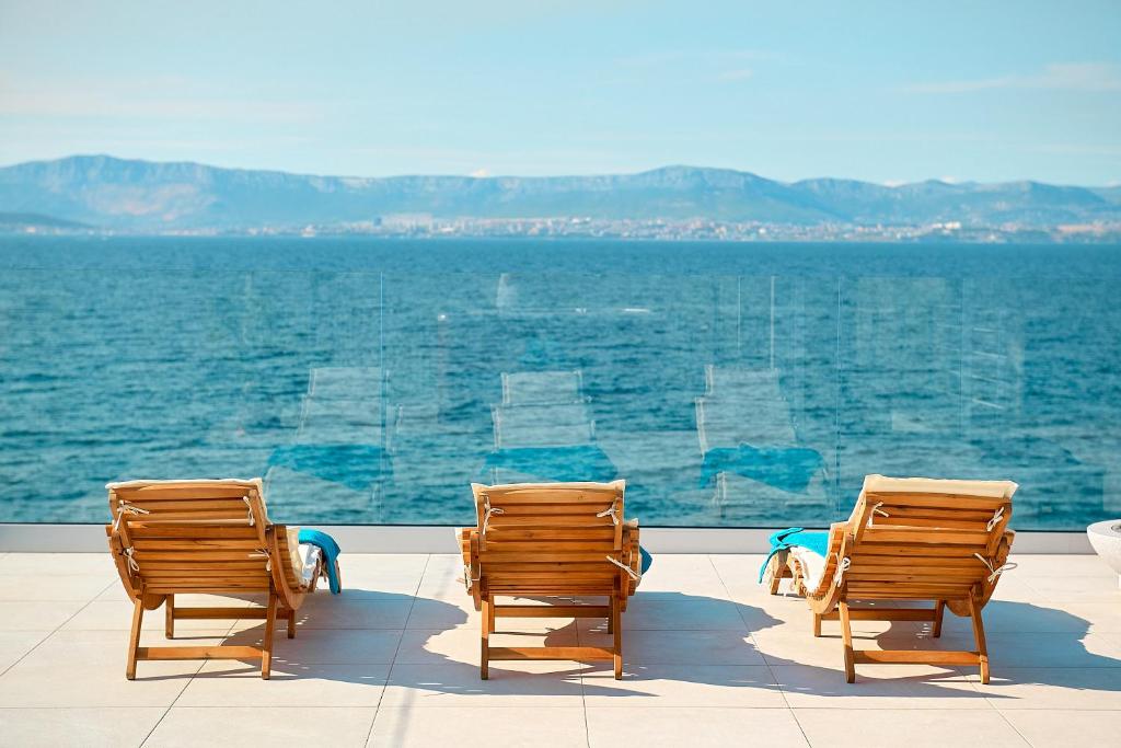 a group of chairs sitting next to the water at SEAFRONT NORTH HOUSE SUTIVAN - new luxury three-bedroom villa - unforgettable panoramic views of the sea - roof terrace with jacuzzi - first row next to the beach and right next to all facilities - secured parking in Sutivan