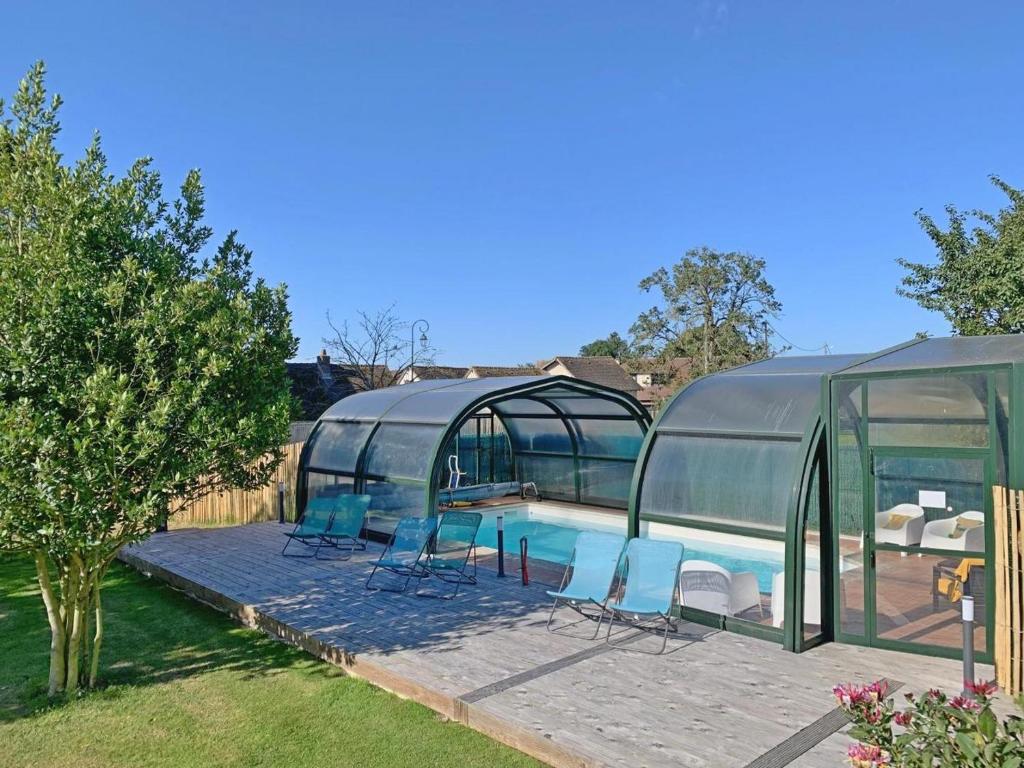 - une piscine dans une maison en verre avec des chaises dans l'établissement Le Bois aux Cerfs, à Bois-Jérôme-Saint-Ouen
