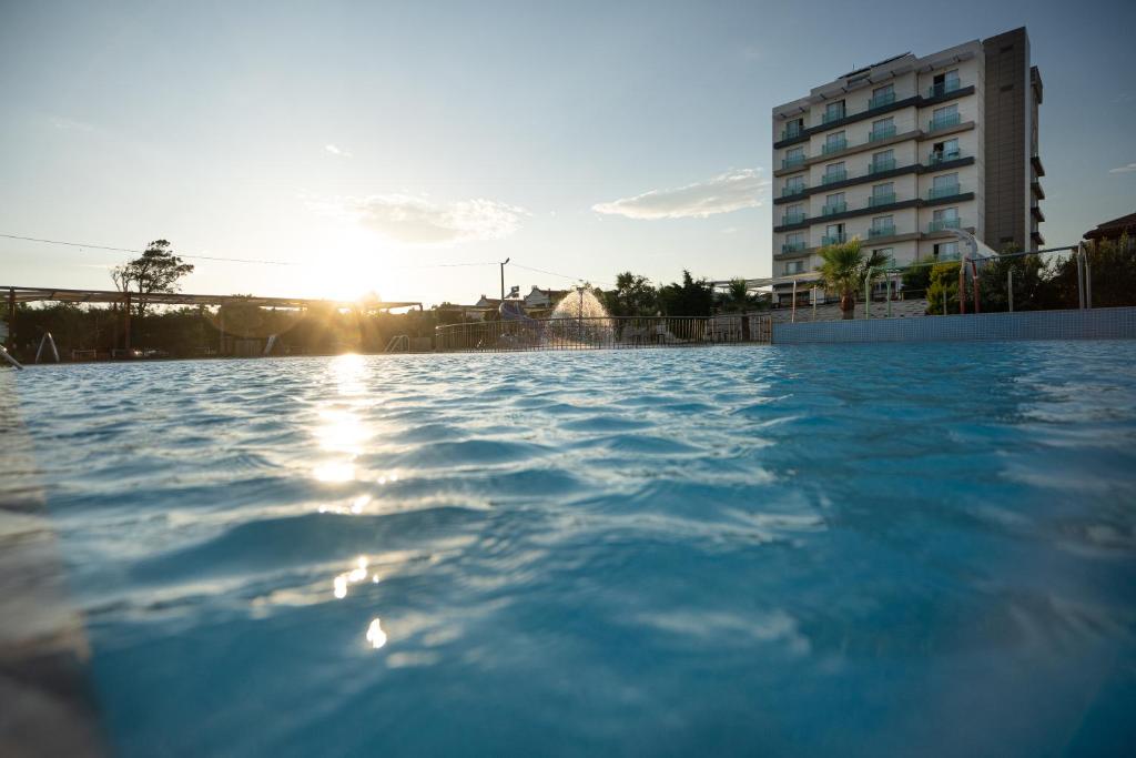 a pool in front of a building with the sun setting at Hotel Musho in Ayvalık
