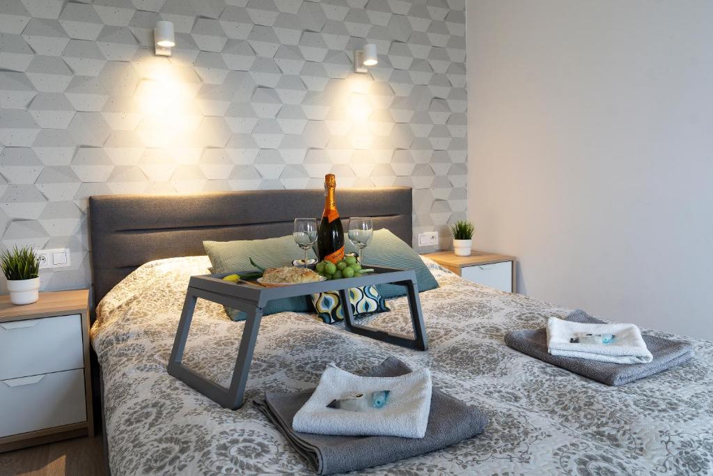 Una cama con una mesa con una botella de vino y copas en Ideal Apartments Grobla, en Gdansk