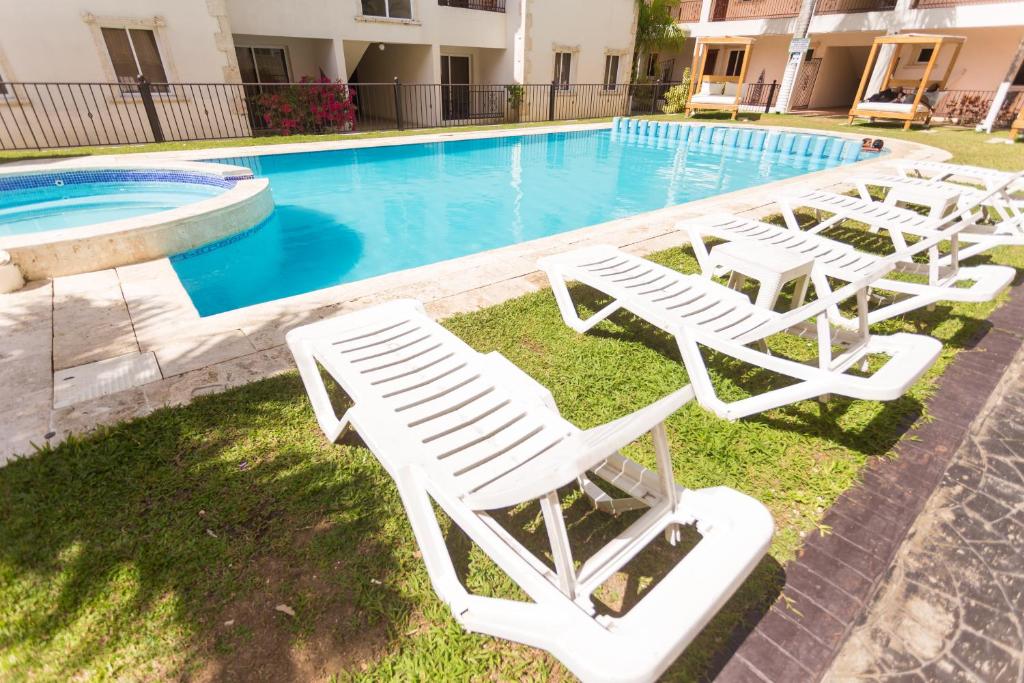 un grupo de tumbonas blancas junto a una piscina en Big apartment whit Pool jacuzzi terrace, en Punta Cana