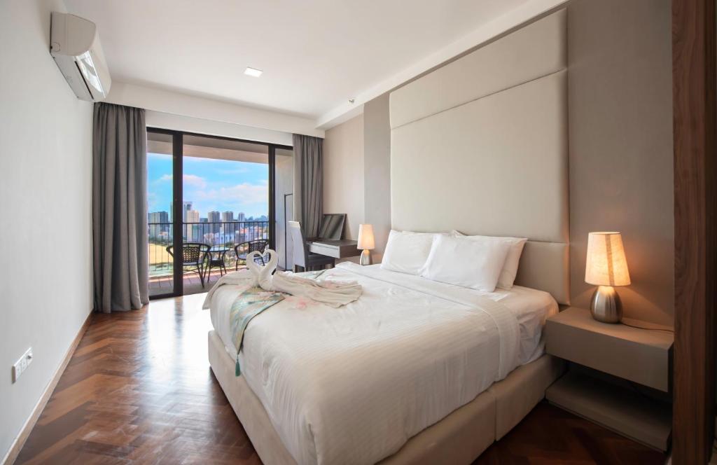 a bedroom with a large white bed and a balcony at The Landmark Penang in Tanjong Tokong