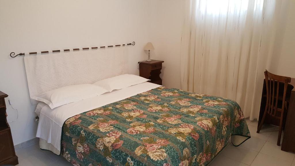 1 dormitorio con 1 cama con colcha de flores en Il Giardino del Nespolo en Alghero