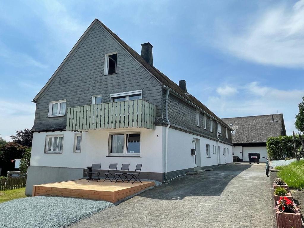 a white house with two benches in front of it at Appartement Neuastenbergerstrasse 4 Neuastenberg in Winterberg