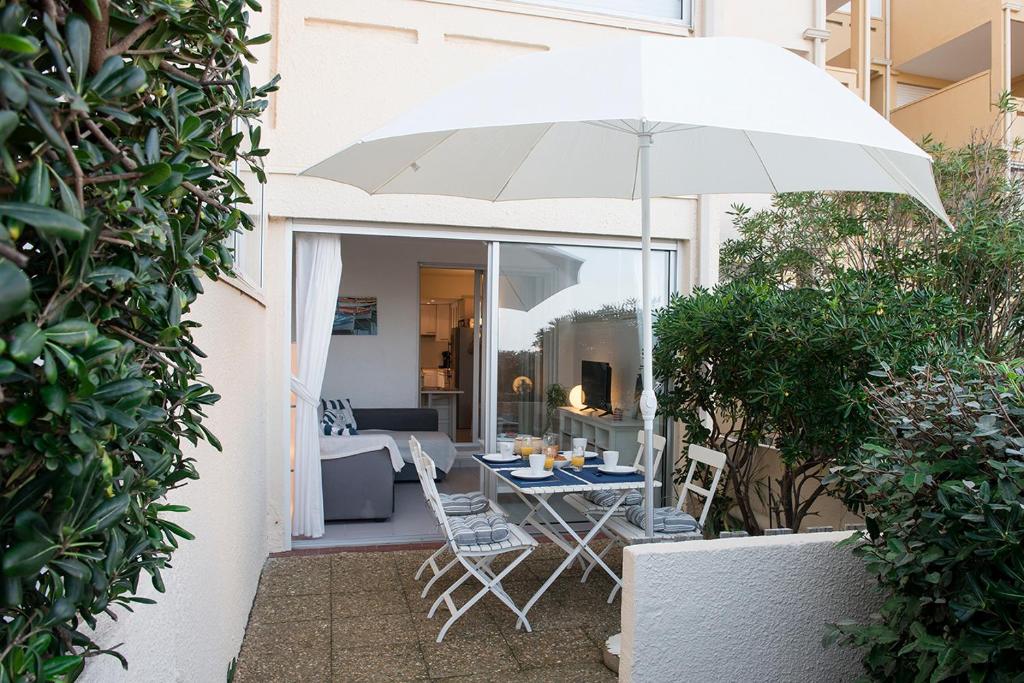 a patio with a table and chairs and an umbrella at L'Aigrette - Front de mer-Accès direct plage in Leucate
