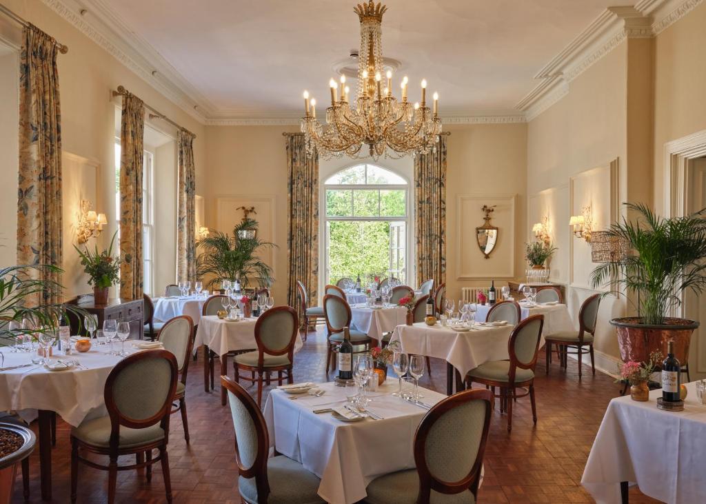 a dining room with tables and chairs and a chandelier at The Arundell in Lifton