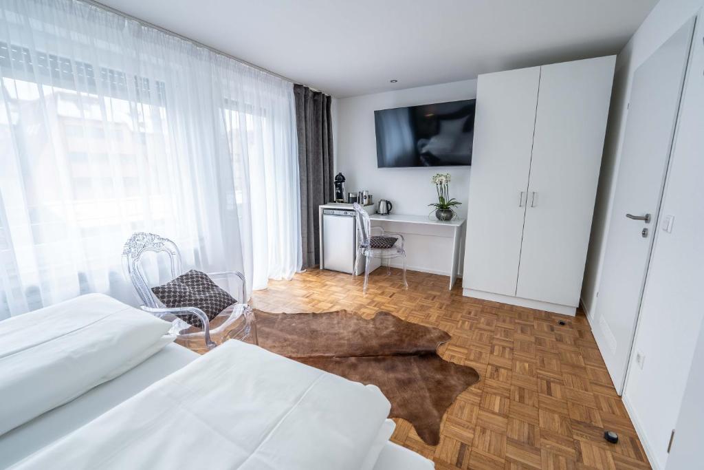 1 dormitorio con 1 cama y TV en la pared en City Apartments FN L 6 KLIMATISIERT mit Balkon - Deluxe Doppelzimmer, en Friedrichshafen