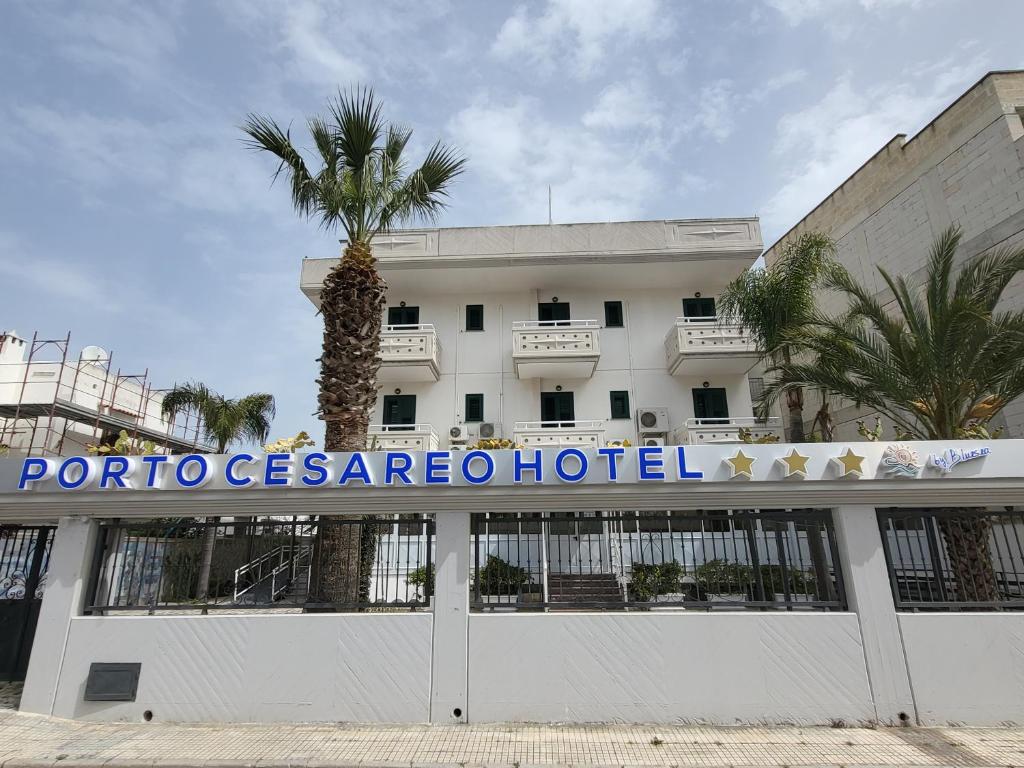 a hotel with a palm tree in front of a building at Porto Cesareo Hotel in Porto Cesareo