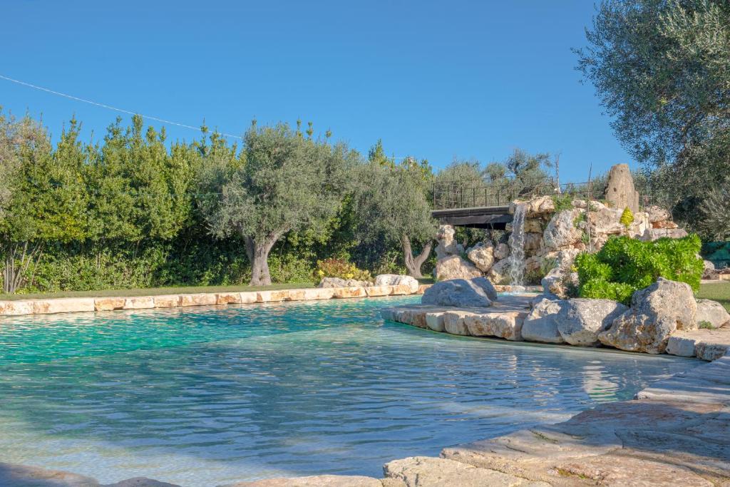 a pool with rocks and a waterfall in the middle of it at Masseria Le Lamie in Villa Castelli