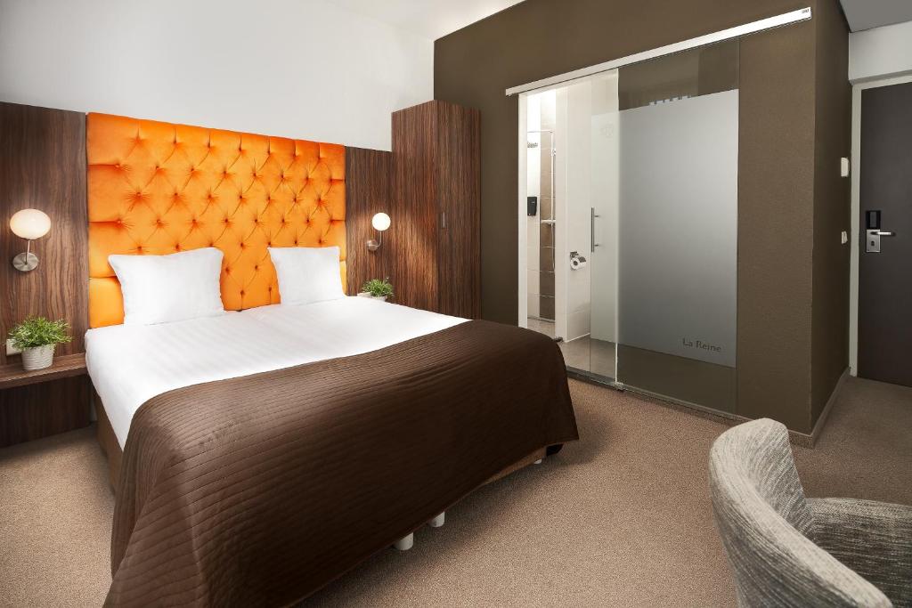 um quarto com uma cama grande e uma cadeira em Hotel La Reine em Eindhoven