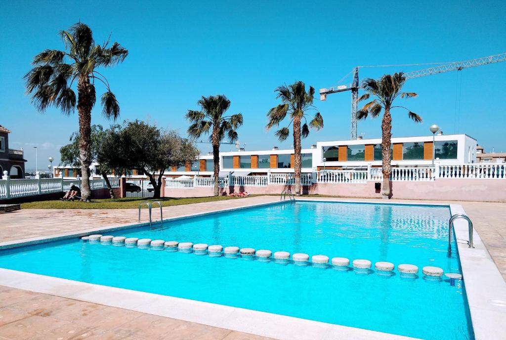 een zwembad met palmbomen en een gebouw bij Nuestra Casa en Gran Alacant in Gran Alacant