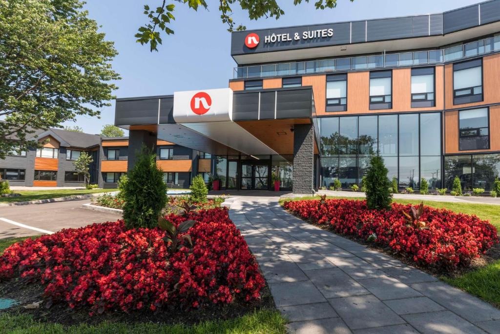 un edificio de hospital con flores rojas delante de él en Hôtel & Suites Normandin Lévis, en Lévis