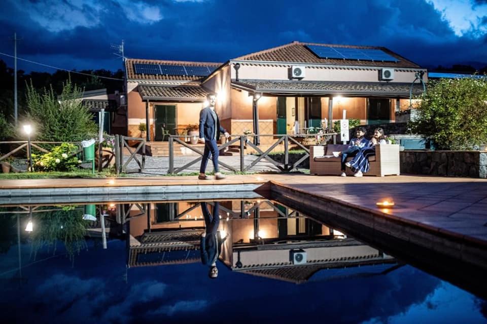 米羅的住宿－Agriturismo Le Case Del Merlo，站在泳池旁房子前面的人
