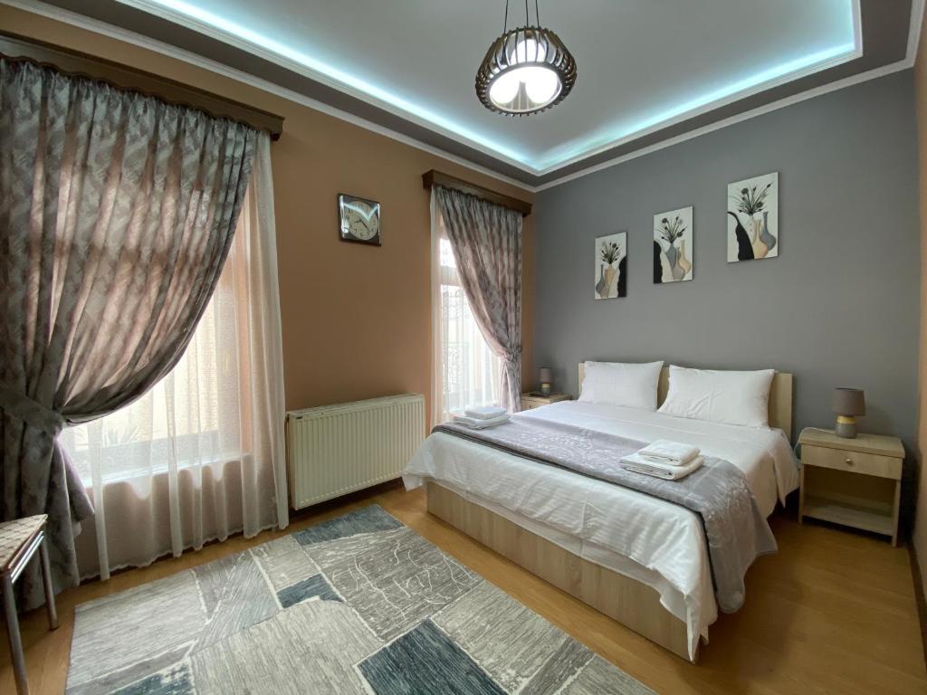 a bedroom with a bed and two windows at Vila A Hotel in Korçë