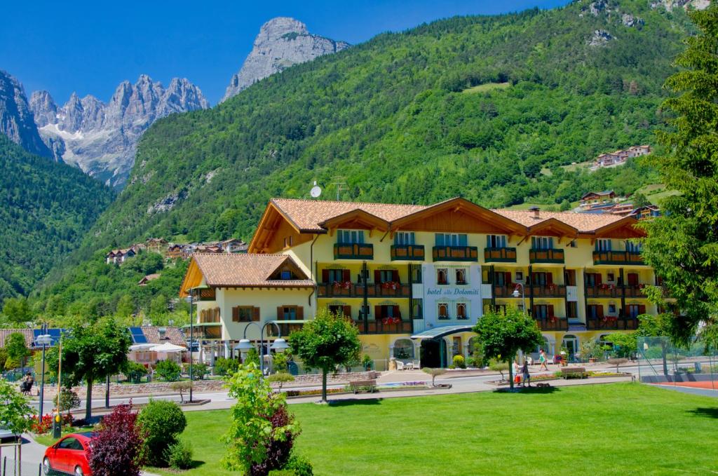 a large hotel with a mountain in the background at Alledolomiti Boutique Lake Hotel in Molveno