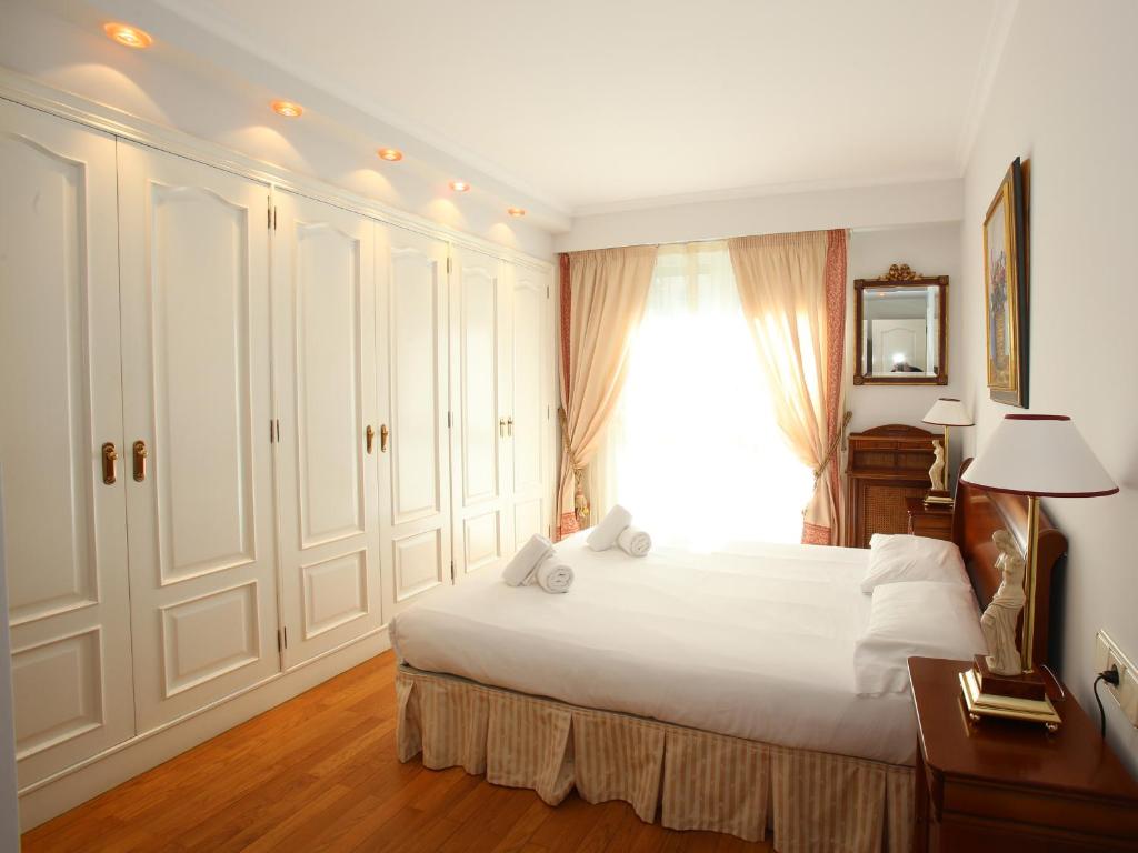 a bedroom with a large white bed and a window at Apartamento Ondarreta in San Sebastián