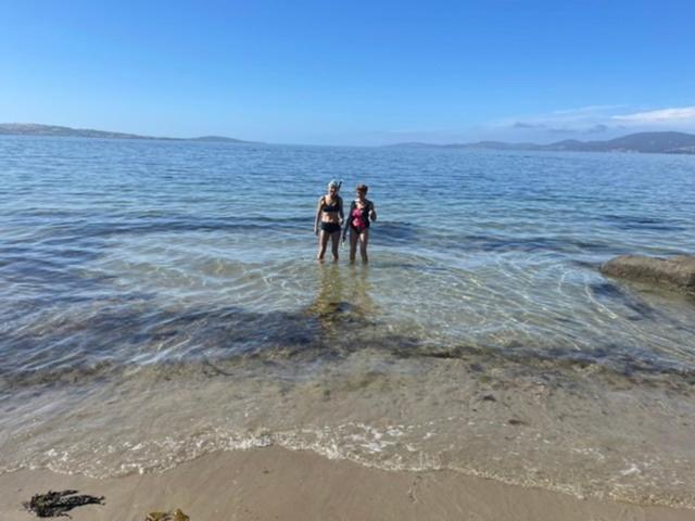 dos mujeres de pie en el agua en la playa en Beachside Taroona with Spa en Sandy Bay