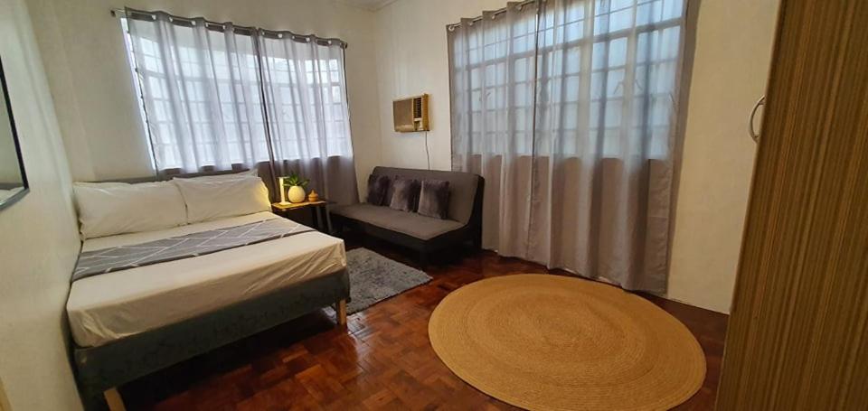 a bedroom with a bed and a chair and a window at San Fabian Vacation Home in Mabilao