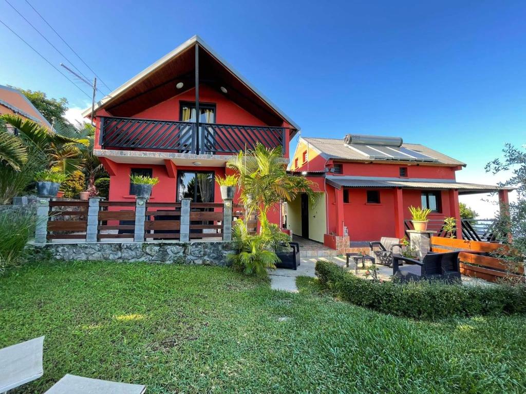 une maison rouge avec une cour devant elle dans l'établissement LES VETYVERS, à Grande Ravine