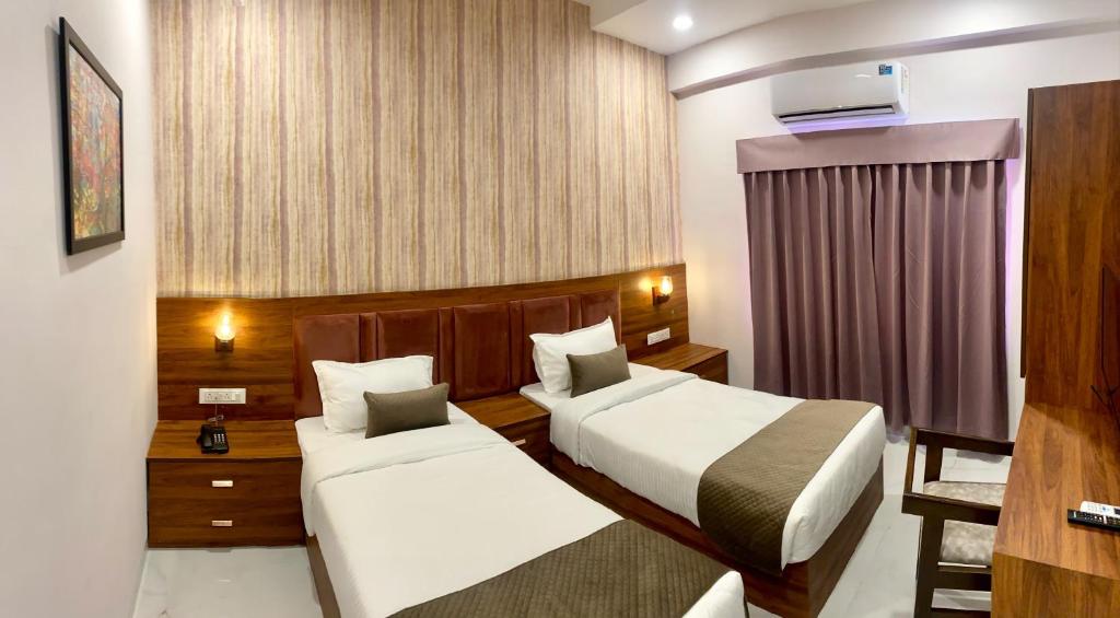 a hotel room with two beds and a window at Hotel Mumbai House-LIG Behind CHL Hospital in Indore
