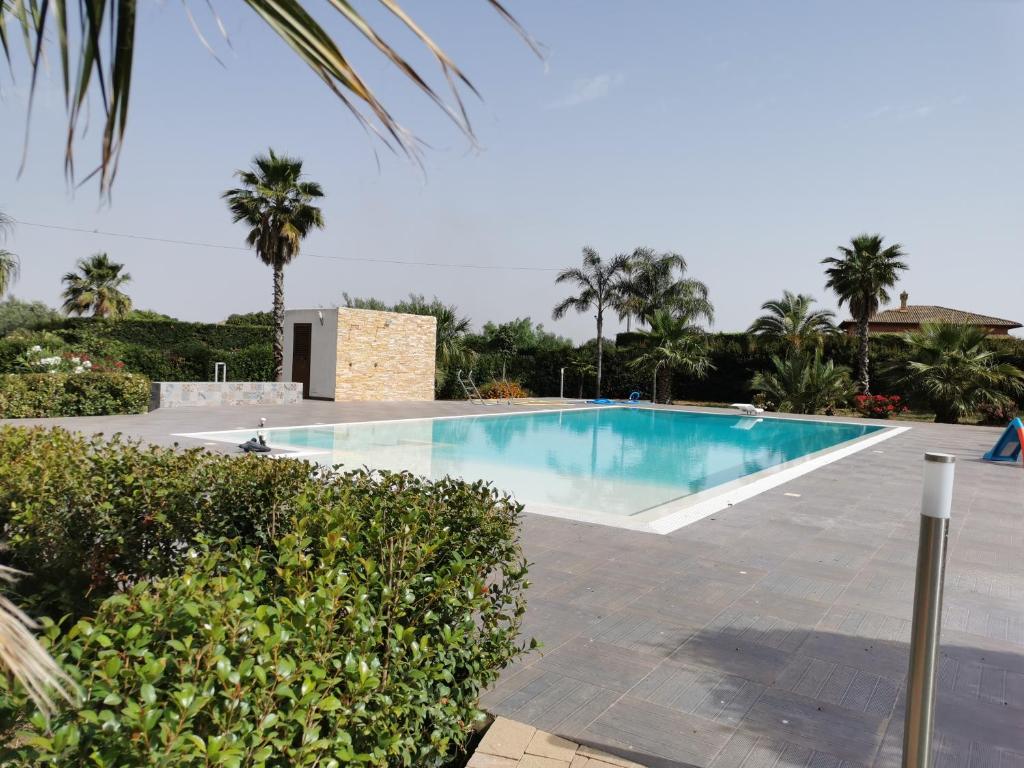 a swimming pool in a resort with palm trees at Villa Patrizia in Canicattì
