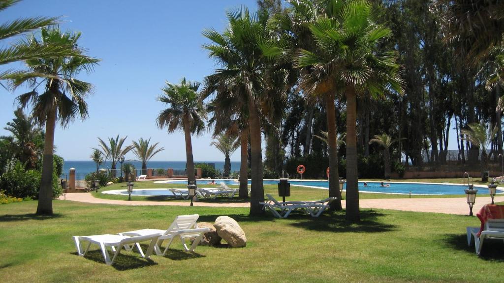 a park with palm trees and a swimming pool at Don Juan Beach Resort in Estepona