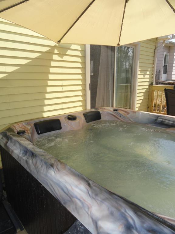 a hot tub with an umbrella in a backyard at Outdoor Hottub, Private Entrance in Lansing