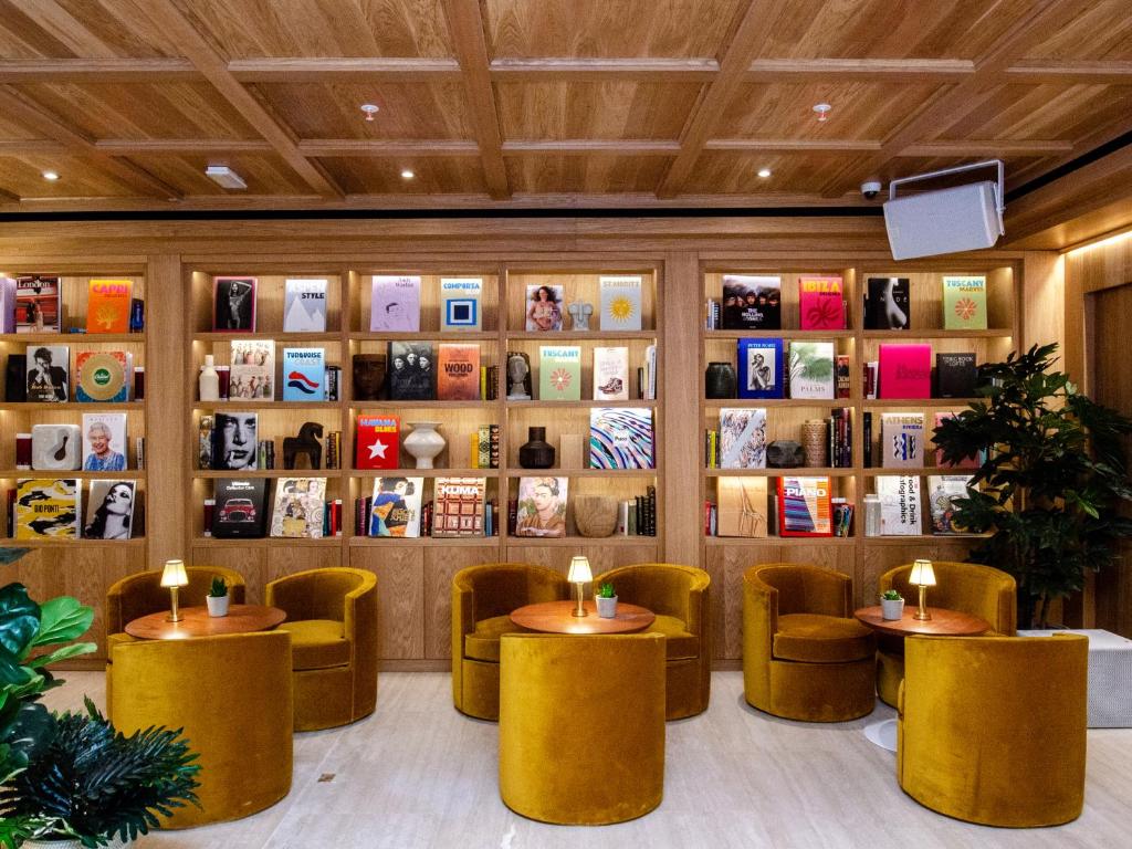 a restaurant with yellow tables and chairs and books at Browns Avenue Hotel in Lisbon